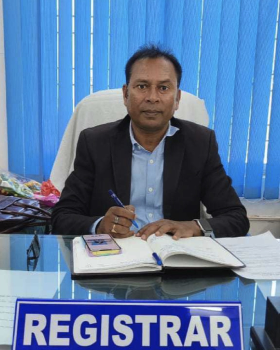 Shri Maheshwar Naik, Registrar of Vikram Dev University, at the Registrar's desk in the administrative wing of the main campus.